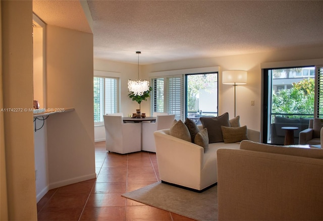 living area with a notable chandelier, light tile patterned floors, baseboards, and a textured ceiling