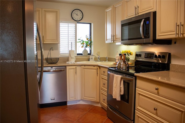 kitchen with cream cabinetry, a sink, stainless steel appliances, light countertops, and light tile patterned floors