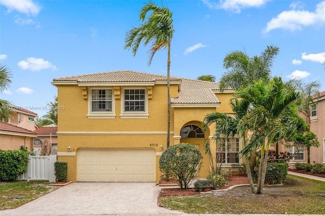 mediterranean / spanish-style house featuring stucco siding, driveway, a tile roof, fence, and an attached garage