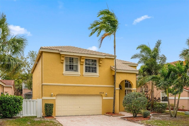 mediterranean / spanish home with decorative driveway, fence, and stucco siding