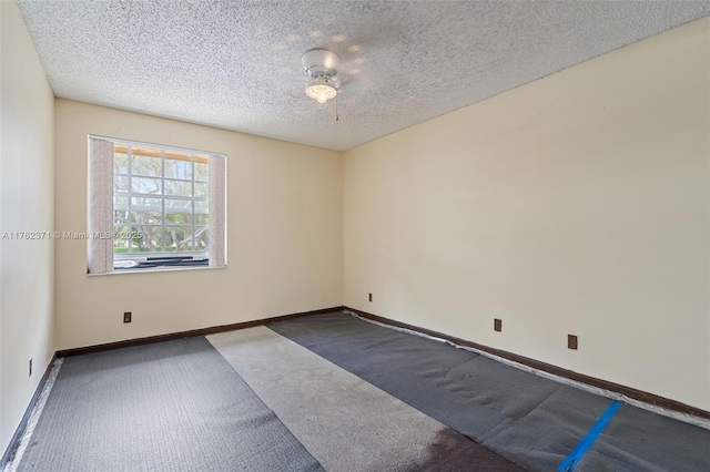 carpeted spare room with a textured ceiling and baseboards