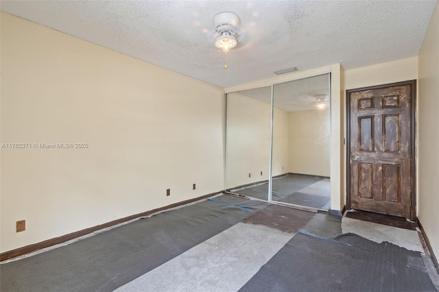 unfurnished bedroom featuring a closet, visible vents, a textured ceiling, and baseboards