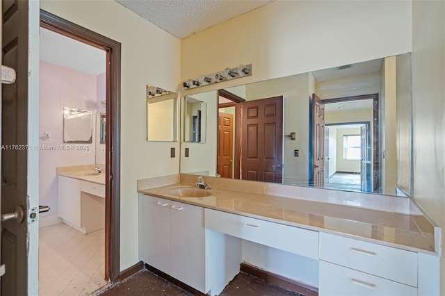 bathroom featuring a textured ceiling, vanity, and baseboards