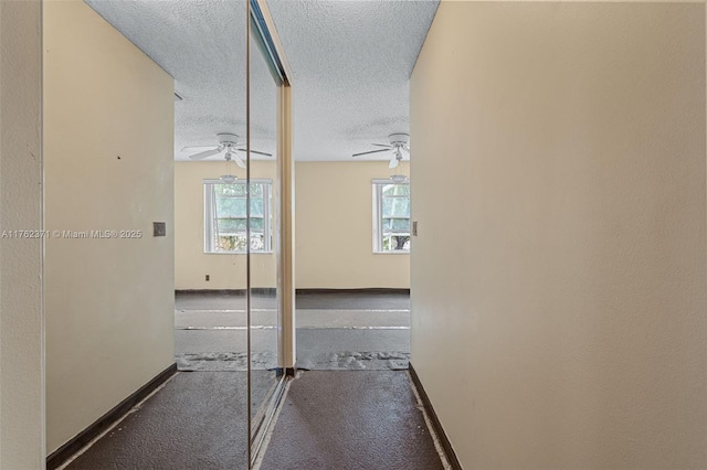 corridor with a textured ceiling and baseboards