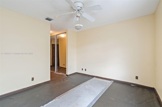 spare room with a textured ceiling, baseboards, visible vents, and ceiling fan