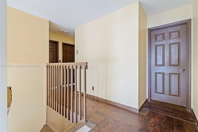 interior space featuring an upstairs landing, a textured ceiling, baseboards, and wood-type flooring