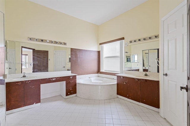 full bathroom with a sink, a garden tub, two vanities, and tile patterned flooring