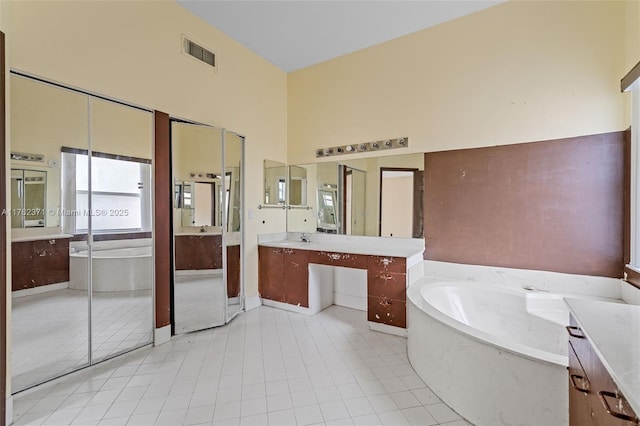 full bathroom featuring visible vents, a garden tub, tile patterned flooring, a towering ceiling, and vanity