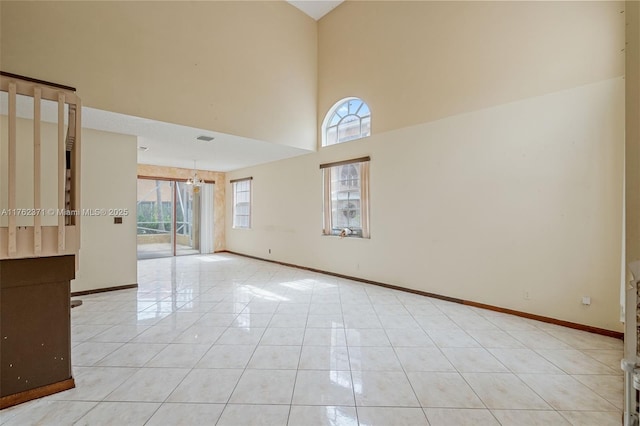 unfurnished room with light tile patterned flooring, visible vents, baseboards, and a towering ceiling