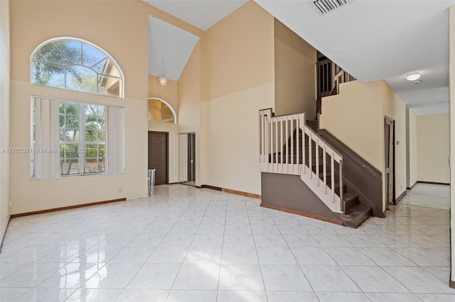 foyer entrance featuring baseboards, visible vents, high vaulted ceiling, stairs, and tile patterned floors