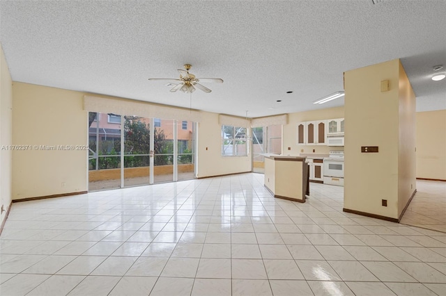 unfurnished living room featuring light tile patterned floors, baseboards, a textured ceiling, and a ceiling fan