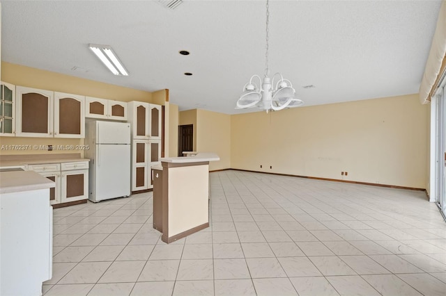 kitchen featuring light tile patterned floors, freestanding refrigerator, light countertops, glass insert cabinets, and open floor plan