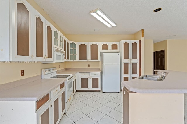 kitchen with a sink, a textured ceiling, white appliances, light countertops, and light tile patterned floors