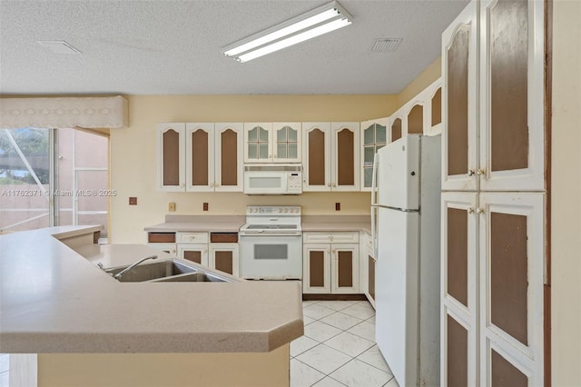 kitchen featuring white appliances, light tile patterned floors, visible vents, a sink, and glass insert cabinets