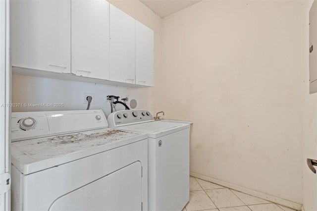 clothes washing area featuring light tile patterned floors, baseboards, cabinet space, and washer and clothes dryer