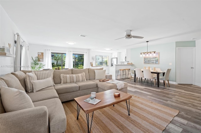 living room featuring visible vents, baseboards, light wood-type flooring, and a ceiling fan