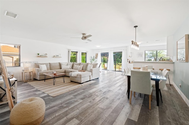 living room with visible vents, an inviting chandelier, baseboards, and wood finished floors