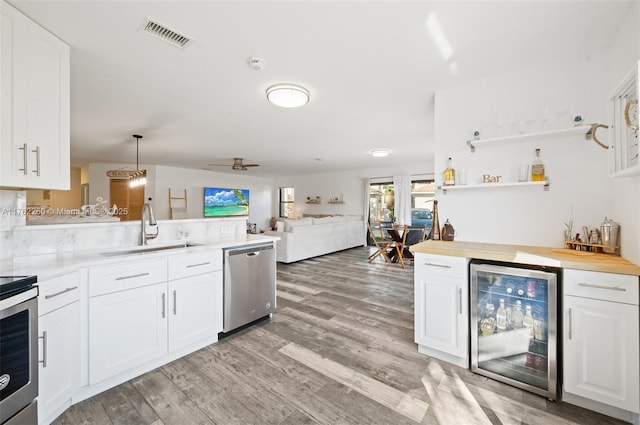 kitchen featuring a sink, light wood-type flooring, dishwasher, and beverage cooler