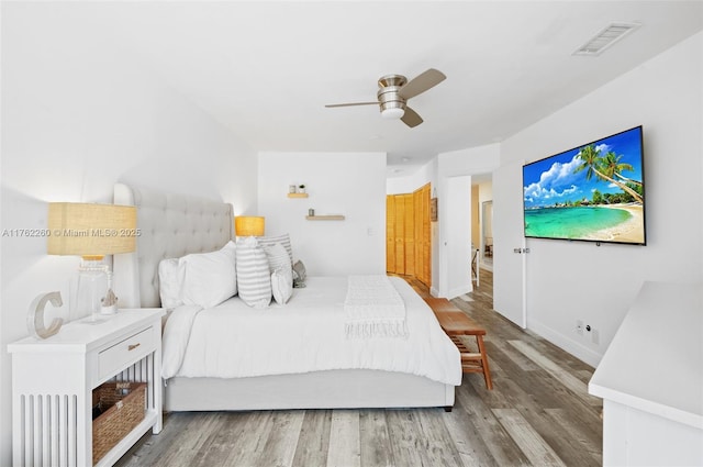 bedroom featuring visible vents, a ceiling fan, baseboards, and wood finished floors