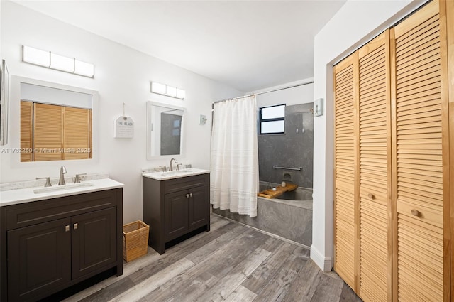 full bath featuring two vanities, wood finished floors, a closet, and a sink