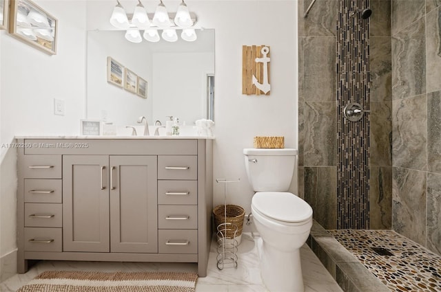 bathroom with a tile shower, marble finish floor, toilet, and vanity