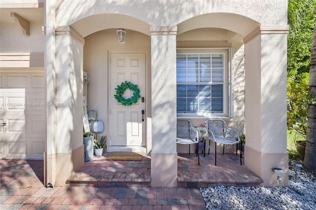 view of exterior entry with stucco siding and a garage