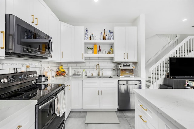 kitchen with backsplash, light stone countertops, appliances with stainless steel finishes, white cabinetry, and a sink