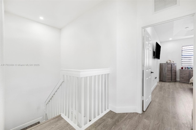 corridor with visible vents, an upstairs landing, wood finished floors, recessed lighting, and baseboards