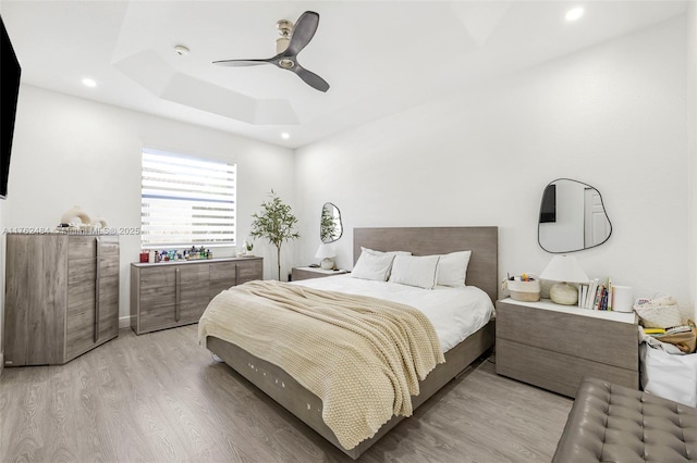 bedroom featuring recessed lighting, light wood-type flooring, a raised ceiling, and ceiling fan