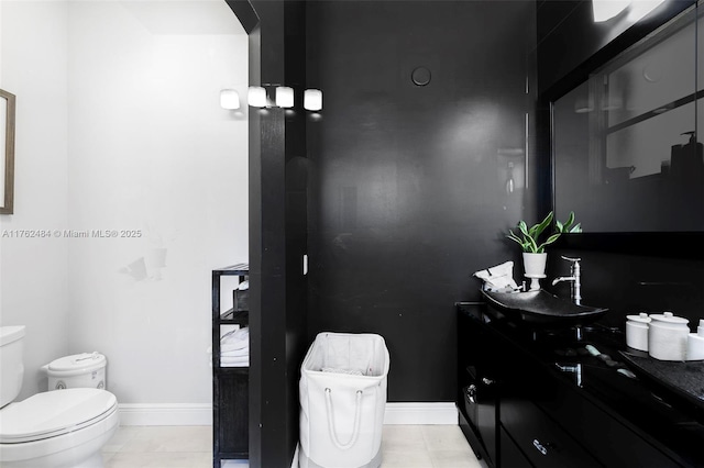 bathroom featuring baseboards, toilet, vanity, and tile patterned flooring