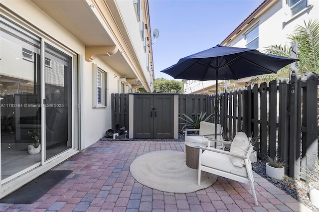 view of patio featuring an outdoor structure, fence, and a shed