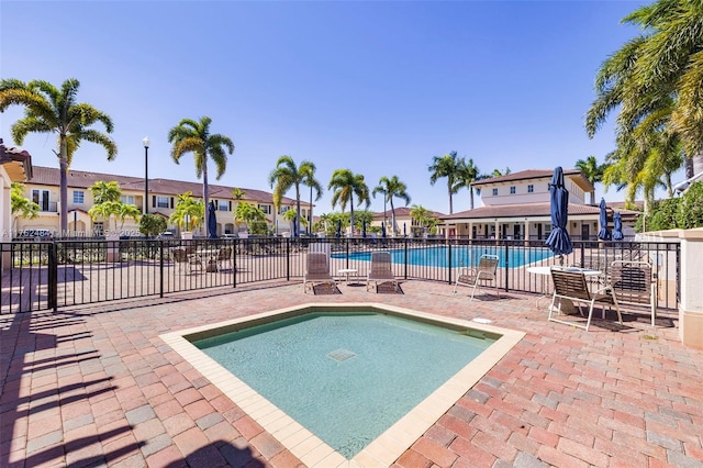 community pool with a patio, fence, and a residential view