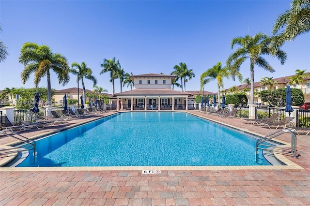 community pool with a patio area and fence