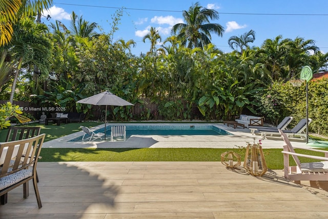 pool featuring a wooden deck, a yard, and a fenced backyard