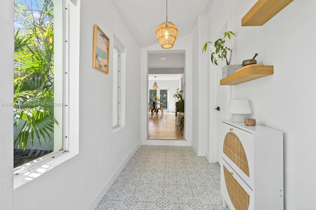 hall featuring an inviting chandelier and baseboards