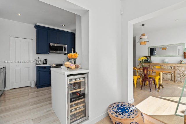 kitchen featuring stainless steel microwave, blue cabinetry, beverage cooler, light countertops, and recessed lighting