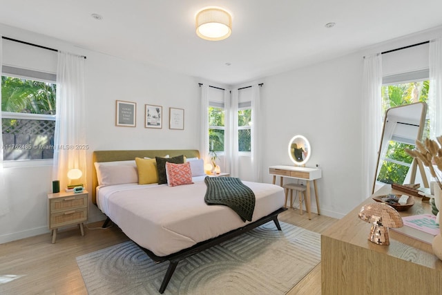 bedroom with multiple windows, baseboards, and light wood-style floors