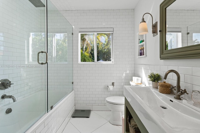 full bathroom featuring a sink, tile patterned flooring, tiled shower / bath combo, tile walls, and toilet