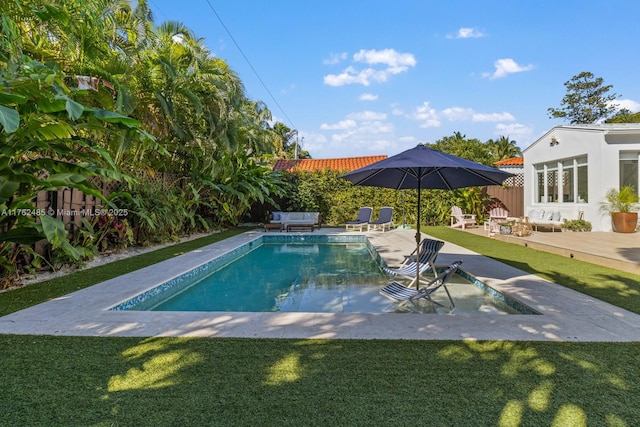 outdoor pool with a patio area, a fenced backyard, and a lawn