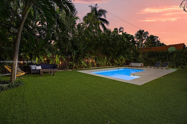 pool at dusk with a patio, fence, a fenced in pool, an outdoor living space, and a lawn