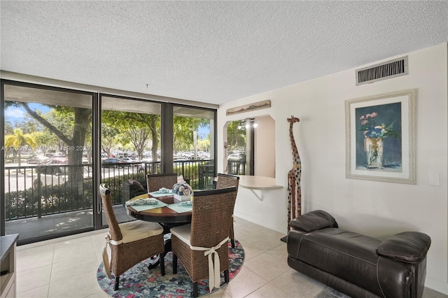 tiled dining room with visible vents and a textured ceiling