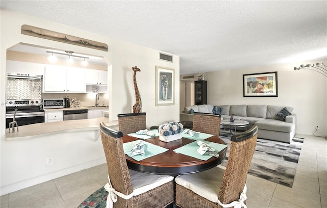 dining area featuring a toaster, light tile patterned floors, visible vents, and a textured ceiling