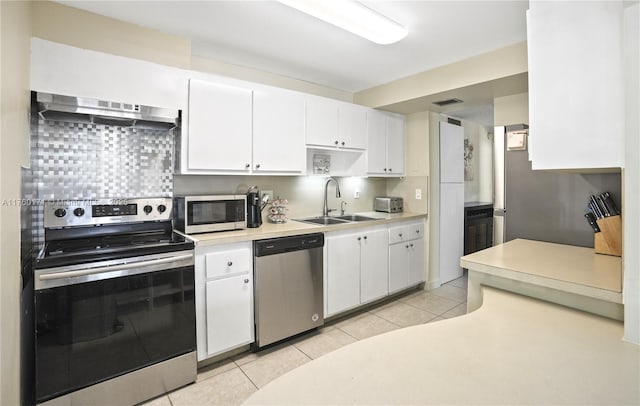 kitchen featuring light tile patterned flooring, a sink, stainless steel appliances, under cabinet range hood, and white cabinetry