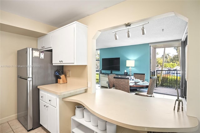 kitchen featuring light countertops, freestanding refrigerator, light tile patterned flooring, white cabinets, and open shelves