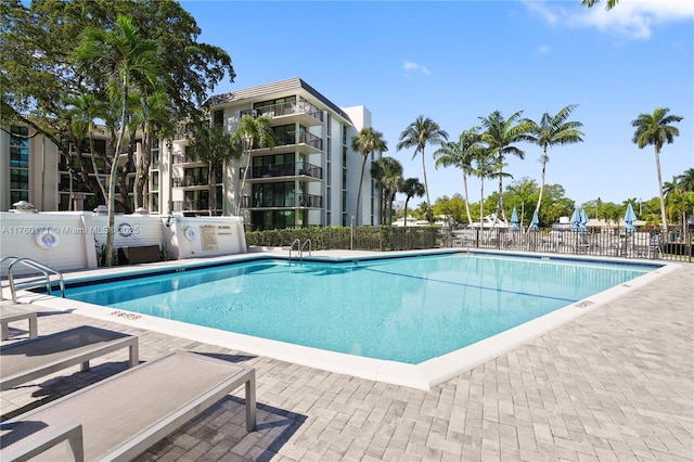 pool with a patio area and fence