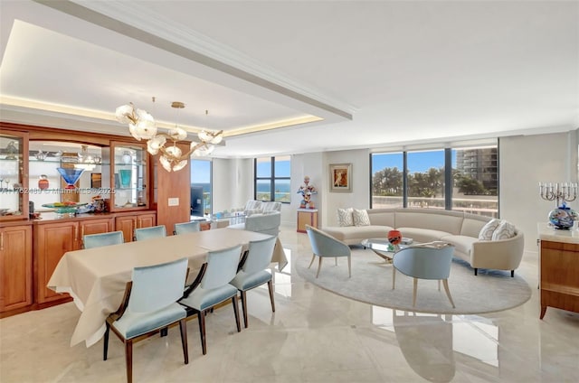 dining space with an inviting chandelier, a raised ceiling, crown molding, and a healthy amount of sunlight