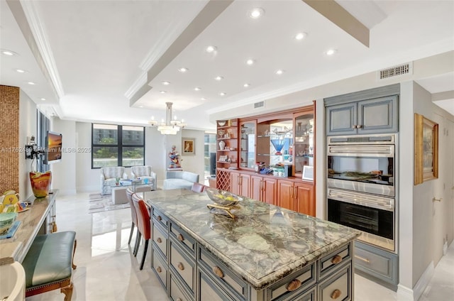 kitchen featuring gray cabinets, light stone counters, open floor plan, stainless steel double oven, and crown molding