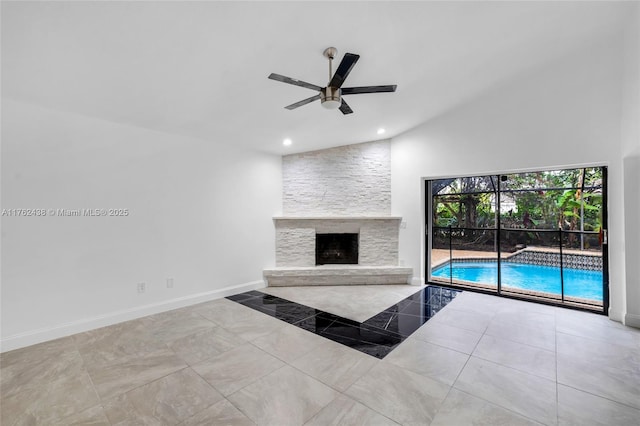 unfurnished living room featuring baseboards, vaulted ceiling, a stone fireplace, recessed lighting, and a ceiling fan