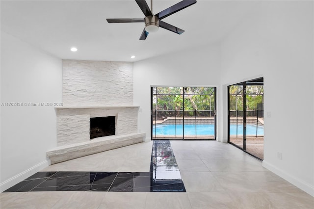 unfurnished living room featuring recessed lighting, a stone fireplace, baseboards, ceiling fan, and vaulted ceiling