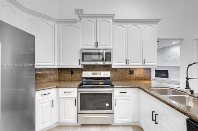 kitchen featuring visible vents, a sink, dark stone countertops, backsplash, and appliances with stainless steel finishes